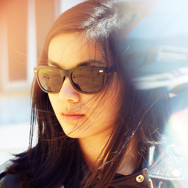 Person wearing sunglasses in sunlight, with long dark hair.