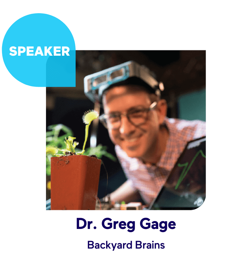 Smiling person with glasses and headgear looking at a plant experiment