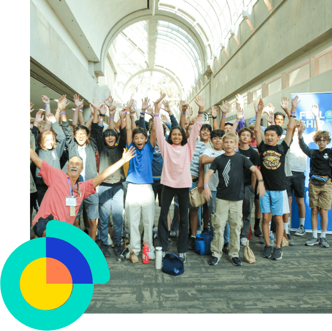 Enthusiastic students and adult posing with hands raised indoors.