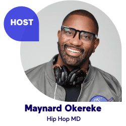 Smiling man with glasses and headphones wearing a gray jacket.