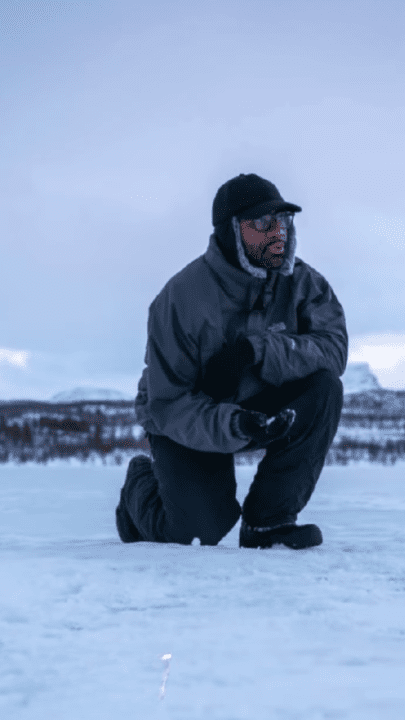 Person kneeling on snowy ground in winter attire outdoors