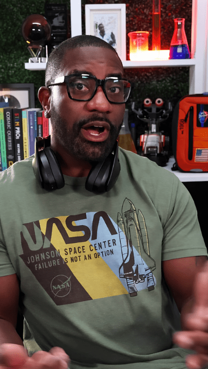 Person with glasses and headphones in a science-themed room.