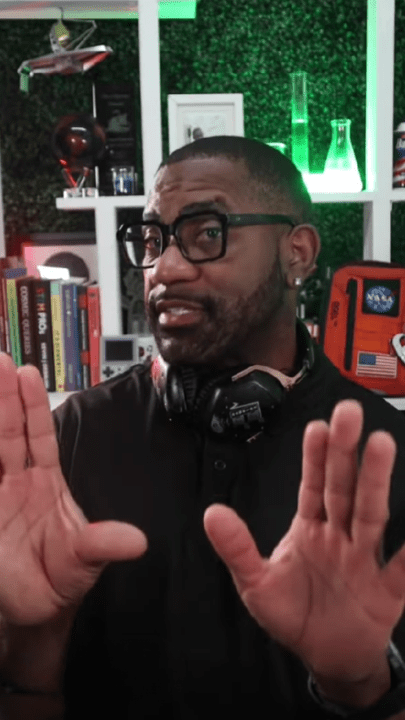 Man in a tech-themed room gestures towards the camera