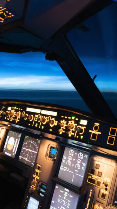 Illuminated cockpit of an aircraft with various controls and displays at twilight.