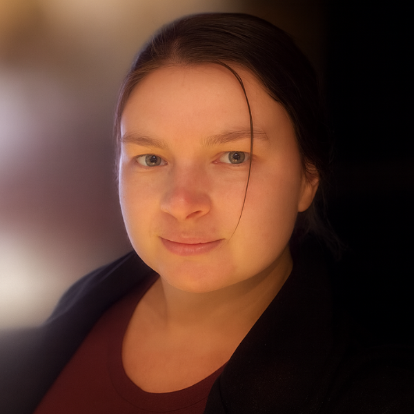 Portrait of a woman with dark hair, soft lighting, and a neutral expression.