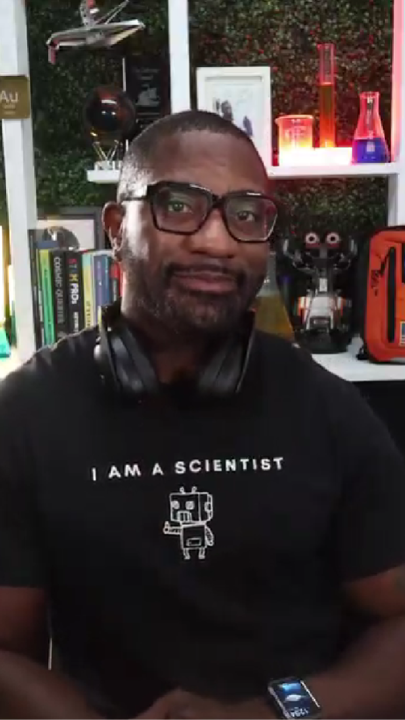 Man in 'I am a scientist' t-shirt with books and lab equipment.