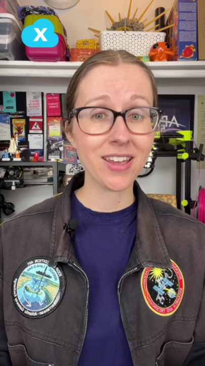 Person in a jacket with patches, standing in a workshop setting.