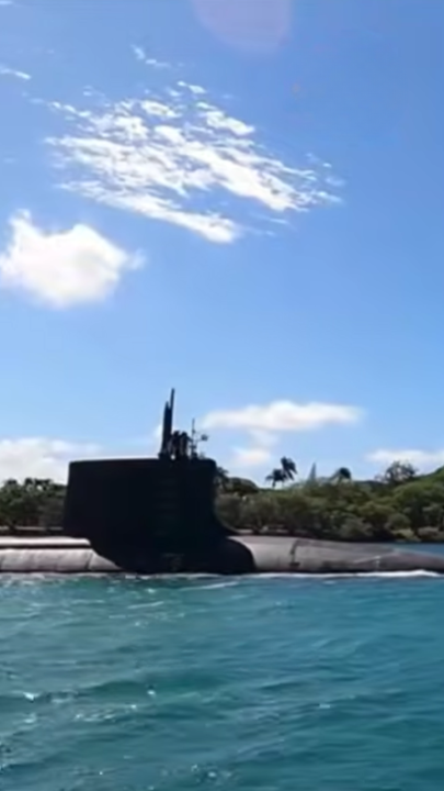 Submarine navigating in clear blue ocean with sky view.