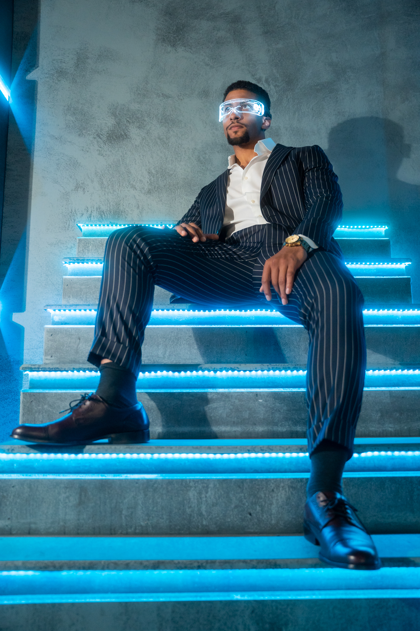 Man in a pinstripe suit sitting on illuminated blue stairs