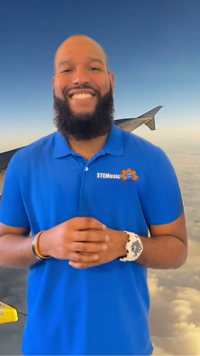 Man smiling on airplane background wearing a blue STEMusic polo.