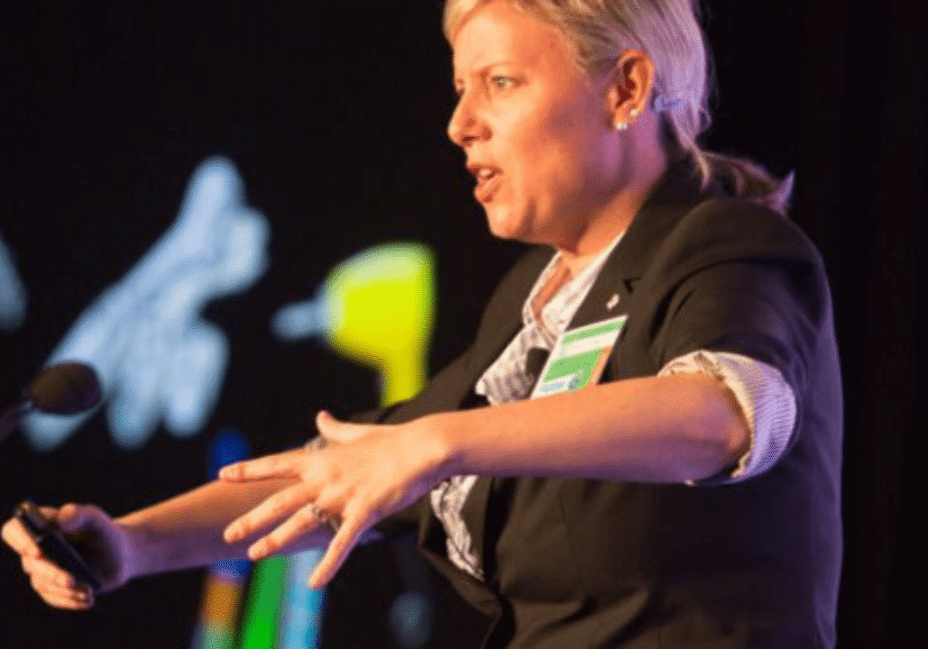 A person speaking passionately at a conference with microphone nearby.