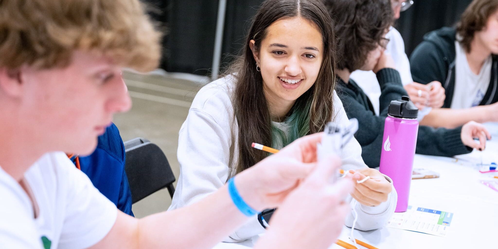 Young woman smiling while working with materials in a group.