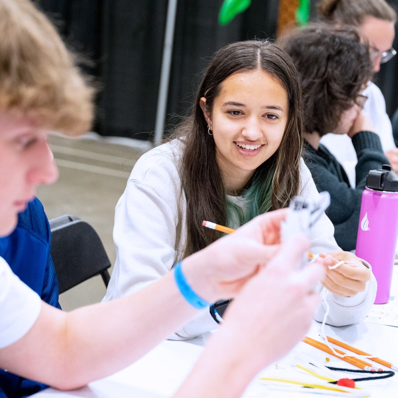 Young woman smiling while working with materials in a group.