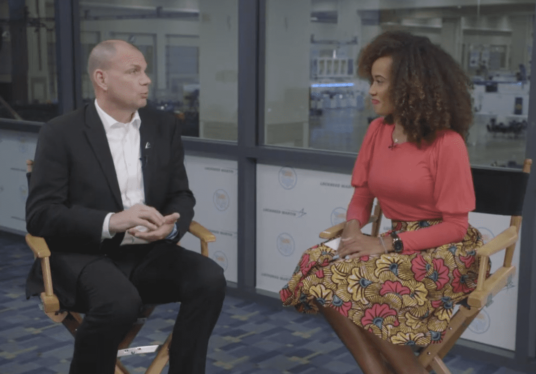 Two people seated in chairs having a conversation indoors.