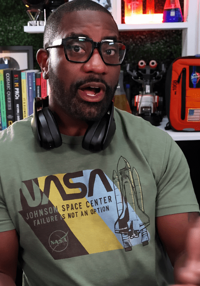 Person with glasses and headphones in a science-themed room.