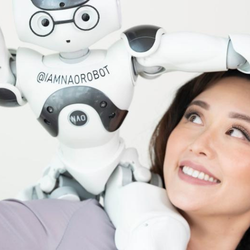 A person smiling next to a friendly robot with glasses and markings.
