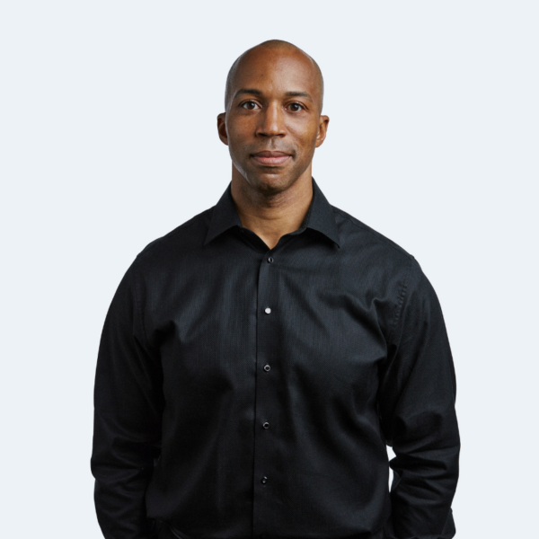 Man in black shirt standing against a plain background.