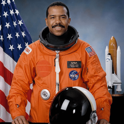 Astronaut in orange NASA suit with helmet and flags
