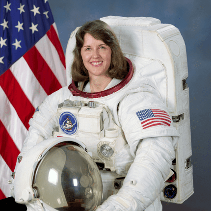 Astronaut in a spacesuit posing with an American flag background.