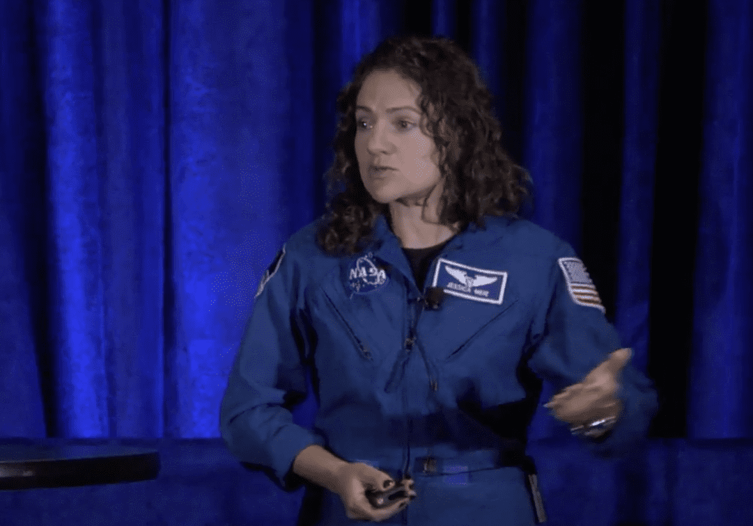 Person in blue astronaut suit speaking on stage.