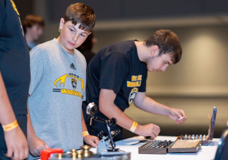 Boy carefully works with precision tools at a workshop.
