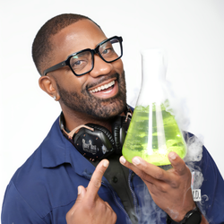 Man smiling while holding a beaker with green liquid and smoke.