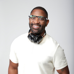 Smiling man in glasses and white shirt with headphones around neck