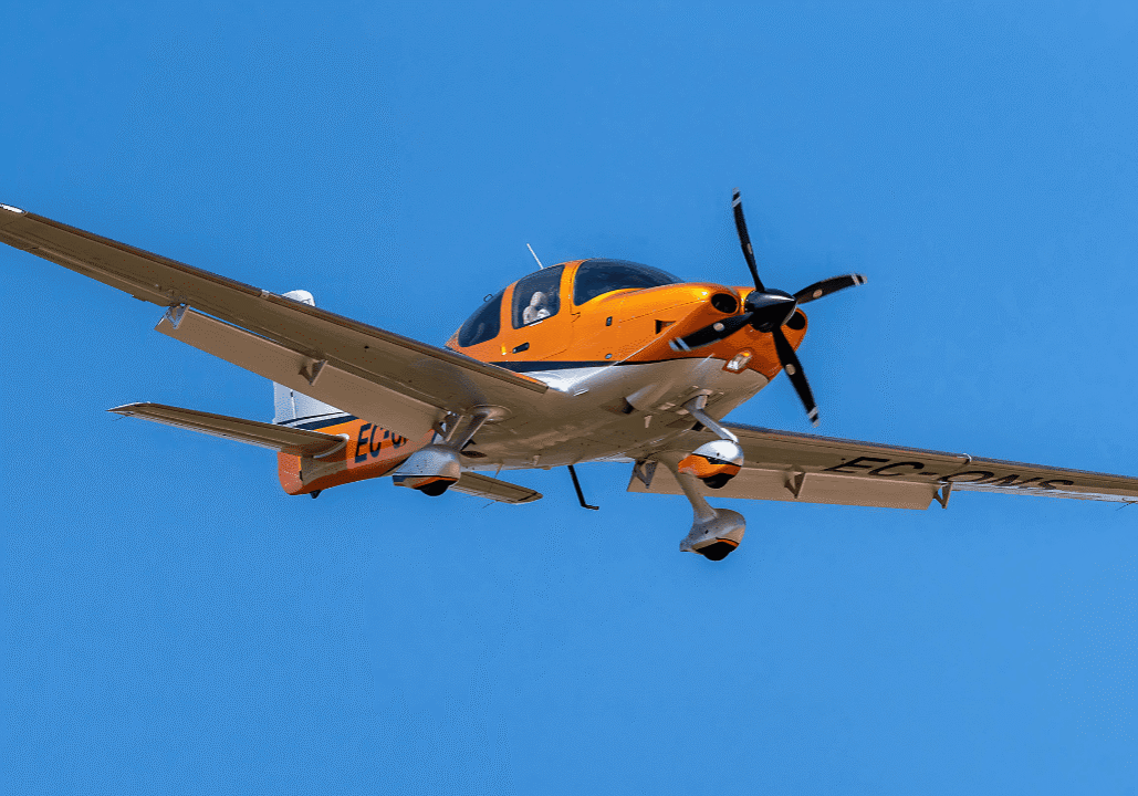 Orange and white small aircraft flying in a clear blue sky.
