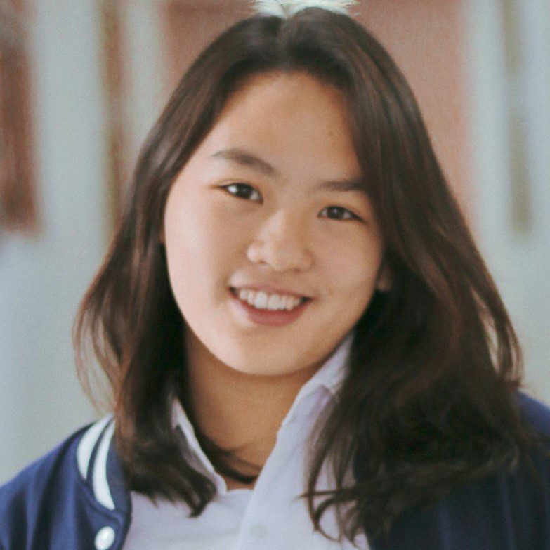 Smiling young woman in a letterman jacket headshot.