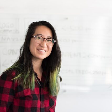 Teacher Christina smiling in glasses against a whiteboard.