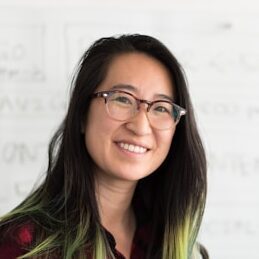 Teacher Christina smiling in glasses against a whiteboard.