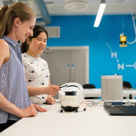Two women working on electronics in a bright modern lab.
